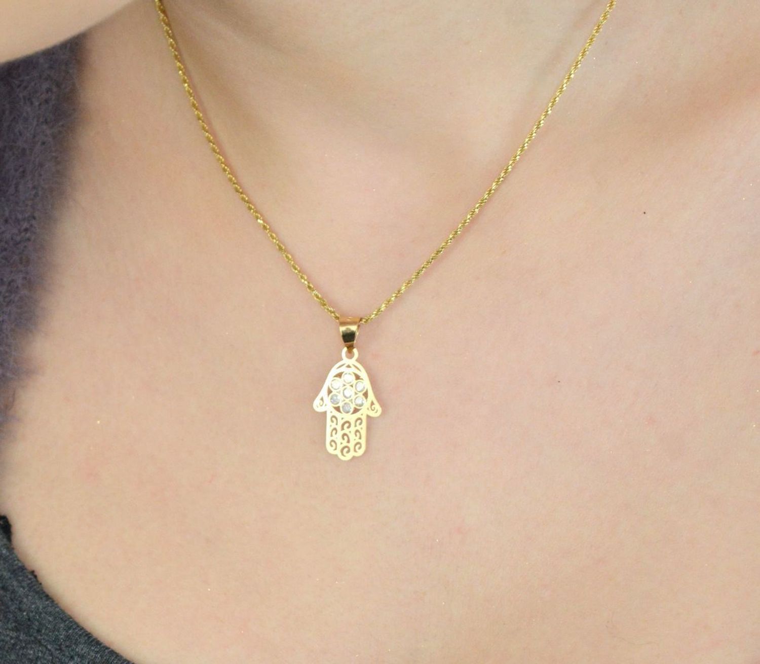 Zawieszka złota Ręka Fatimy próby 585, zdobiona cyrkoniami. Wymiary 2,5×1,3 cm, waga 0,61 g. Idealna jako prezent lub talizman ochronny.1.jpg